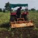 Farmers rotate rotavators on soybean crops